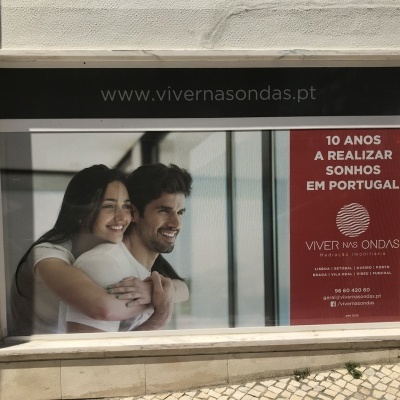 Painel publicitário com casal sorridente e texto promocional em português