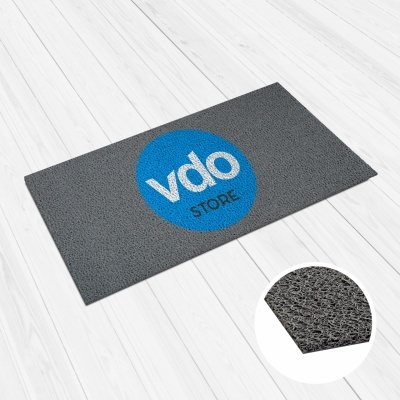 Tapete cinzento com logótipo azul e branco no centro sobre chão de madeira clara