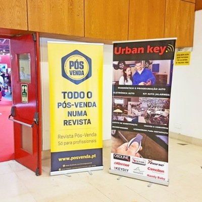 Dois roll-ups publicitários num interior com chão claro e paredes brancas