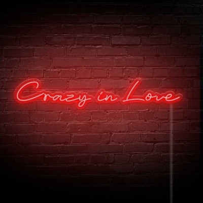 Letreiro em neon vermelho com texto 'Crazy in Love' em parede de tijolos pretos