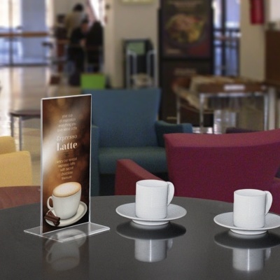 Mesa com duas chávenas de café e expositor com publicidade de espresso latte numa cafeteria