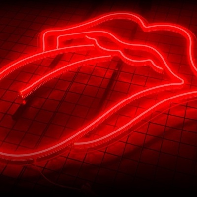 Neón vermelho em forma de lábios com língua numa grade metálica