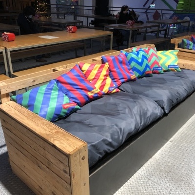 Sofá de madeira com almofadas coloridas listradas e assento cinza