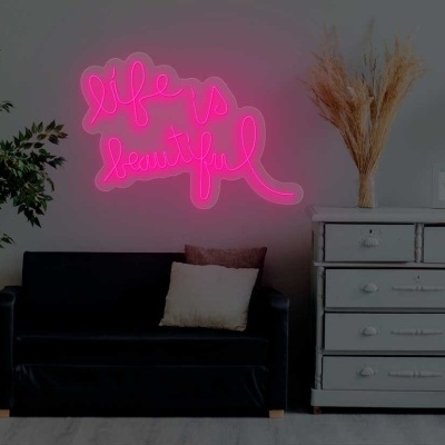 Sala de estar com sofá preto, cómoda branca, candeeiro preto e decoração neon rosa
