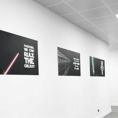 Parede branca com quadros pretos e textos em inglês numa sala iluminada