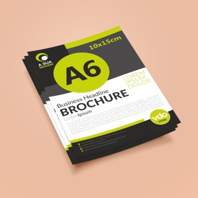 Brochura A6 com design verde, negro e branco sobre superfície pêssego