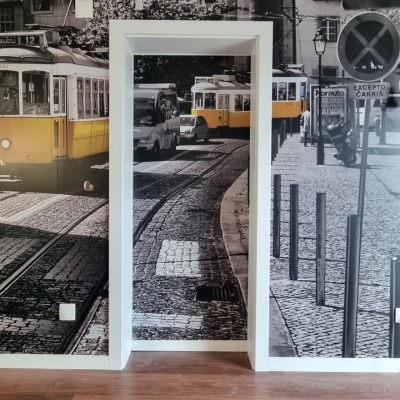 Papel de parede com imagem de elétrico amarelo em cidade, chão de madeira e porta branca