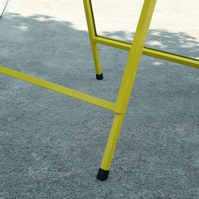 Pernas metálicas amarelas com pontas pretas, chão de betão cinzento