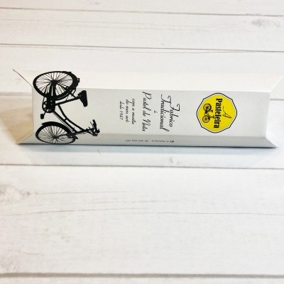 Pacote branco com desenho de bicicleta e selo amarelo sobre fundo de madeira clara