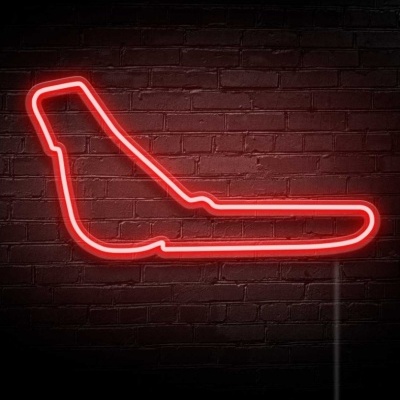 Neon vermelho em forma de banco de motocicleta numa parede de tijolos vermelhos