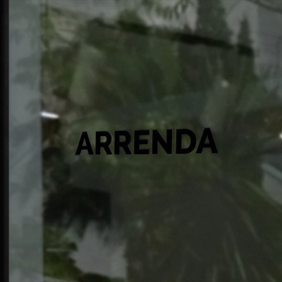 Palavra ARRENDA em vidro de porta com reflexos de árvore e escadas