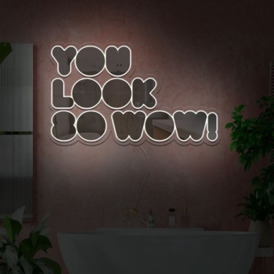 Luminária de parede de néon com o texto YOU LOOK SO WOW! numa parede rosa acima de uma banheira branca