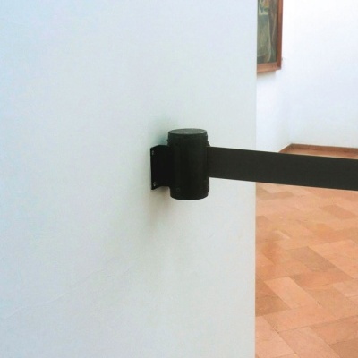 Barreira preta de metal fixada numa parede branca