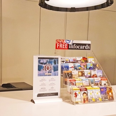 Expositor de acrílico com cartões informativos e sinalização 'FREE infocards' num balcão branco