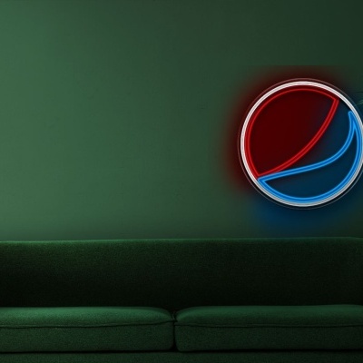 sofá verde escuro, planta em vaso cinzento, logo luminoso da Pepsi na parede