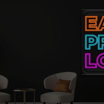 Parede preta com luz de néon colorida e duas cadeiras brancas com almofadas e mesa entre elas.