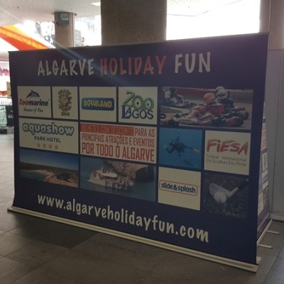 Painel publicitário de atrações do Algarve com vários logotipos em fundo azul numa área interior