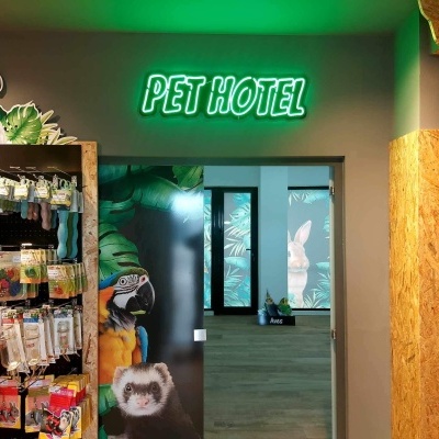 Interior de loja com letreiro 'PET HOTEL' verde e produtos para aves em prateleiras