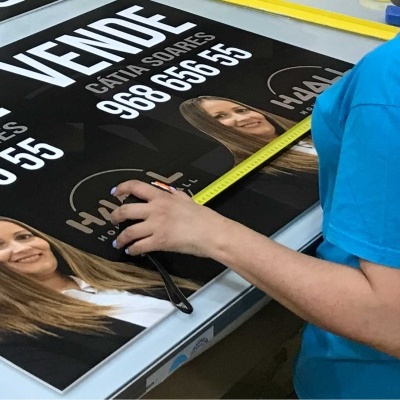 Placas de venda de imóveis com fotos e números de telefone