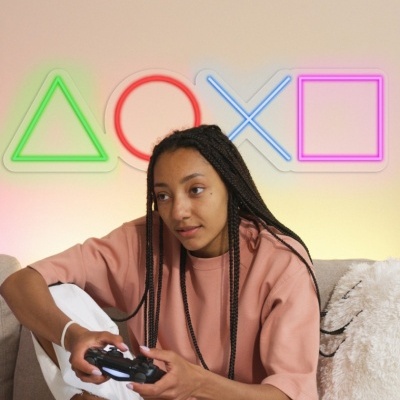 Pessoa a jogar videojogos no sofá com luzes de néon coloridas ao fundo