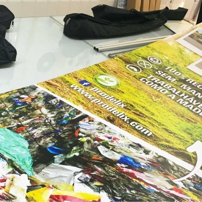 Cartaz dobrado sobre mesa com texto em português e imagem de lixo plástico