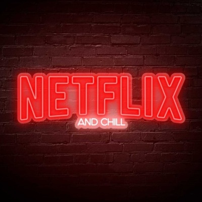 Letreiro de néon com as palavras NETFLIX AND CHILL em parede de tijolo.