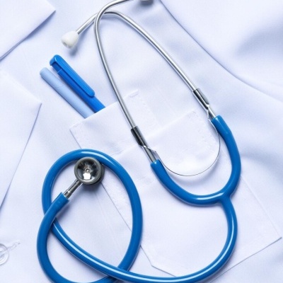 Estetoscópio azul sobre uniforme médico branco com canetas azuis no bolso