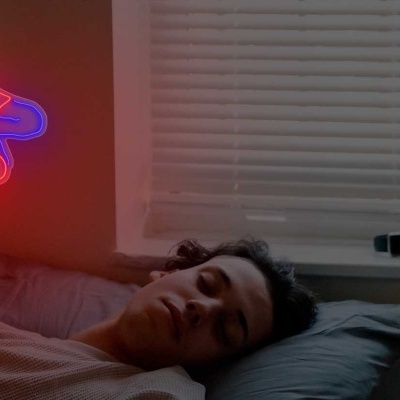 Pessoa a dormir com lâmpada de néon Homem-Aranha invertido