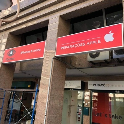 Fachada de loja com placas vermelhas e texto relacionado com reparações Apple e iPhones
