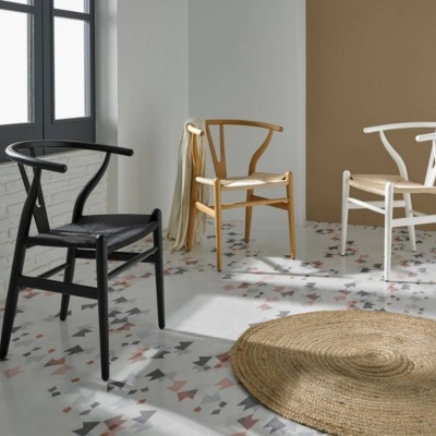 Três cadeiras modernas preta, madeira clara e branca em piso geométrico com tapete redondo de fibras