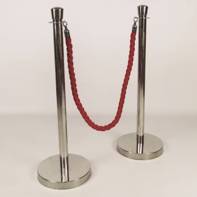Estacas metálicas prateadas com corda vermelha trançada entre elas