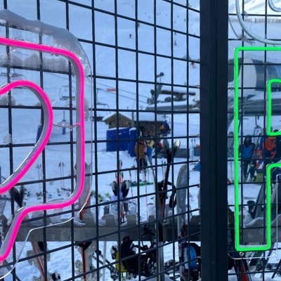 Autocolantes em néon rosa e verde num vidro com fundo exterior nevado e pessoas.