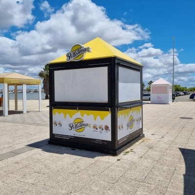 Quiosque de venda ao ar livre com tecto amarelo e logotipo 
