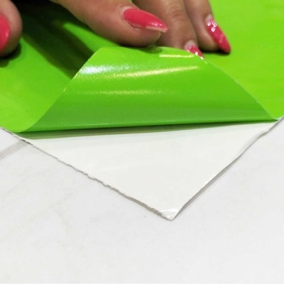 Folha verde fluorescente sendo destacada de superfície branca