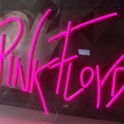 Sinal de néon rosa com texto 'PINK FLOYD' numa parede escura