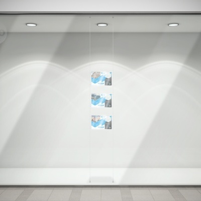 Montra de loja vazia com iluminação e três folhas de papel coladas na parede