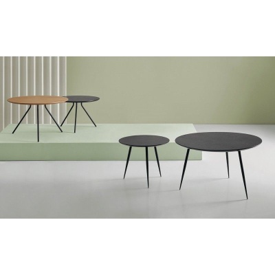 Quatro mesas de centro redondas com tampo preto e de madeira em fundo verde