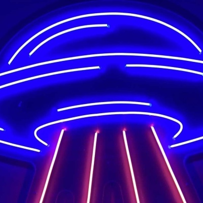 Neon azul e rosa com forma de disco voador numa parede escura