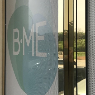 Superfície translúcida com círculo e texto BME ao lado de porta de vidro refletiva