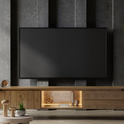 Sala de estar com móvel de madeira clara, televisão preta, planta em vaso preto, candeeiro de pé bege e luz de néon temática.