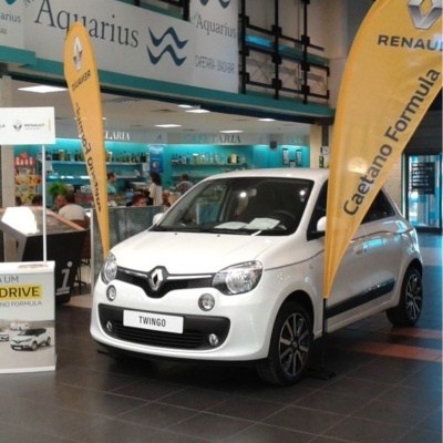 Carro Renault Twingo branco em showroom com bandeiras amarelas Caetano Fórmula