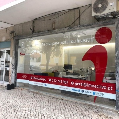 Fachada de escritório imobiliário com janela grande e gráfica vermelha e branca