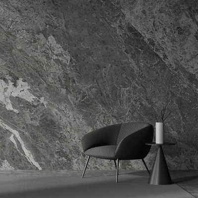 Cadeira cinza escura perto de mesa lateral preta com vaso branco em parede de pedra cinza