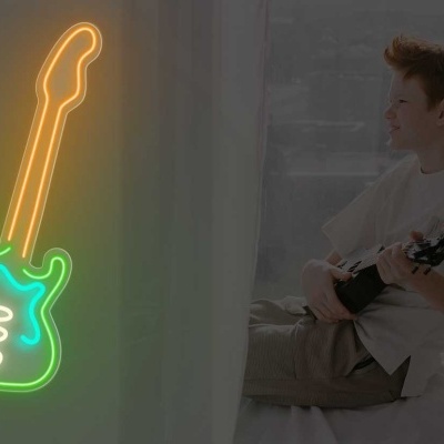 Neon de guitarra elétrica colorida na parede com rapaz a tocar instrumento no chão