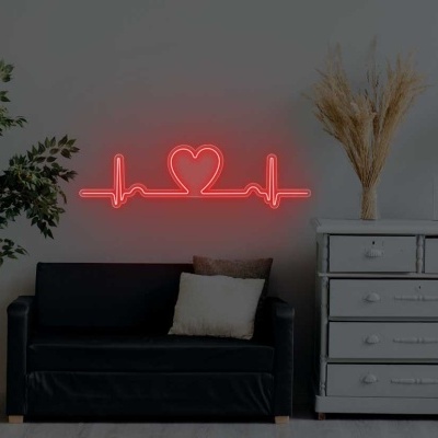 Sala com sofá preto, cómoda cinzenta, plantas e luz de néon vermelha com forma de pulso e coração