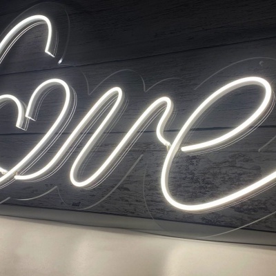 Letreiro luminoso neon branco com a palavra 'Love' em caligrafia cursiva