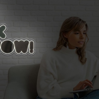 Mulher num sofá a usar portátil com letreiro iluminado no fundo a dizer YOU LOOK SO WOW