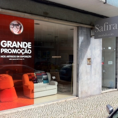 Montra de loja com anúncio de grande promoção e sofás em exposição