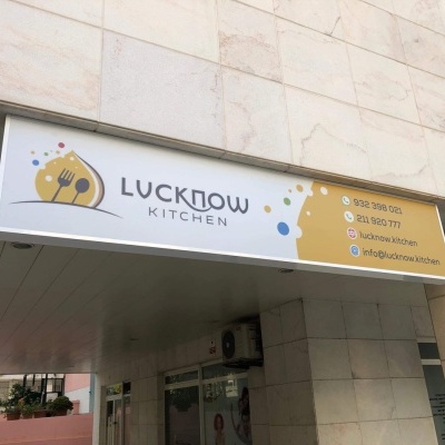 Letreiro de restaurante Lucknow Kitchen com contactos e logótipo sobre parede de azulejos