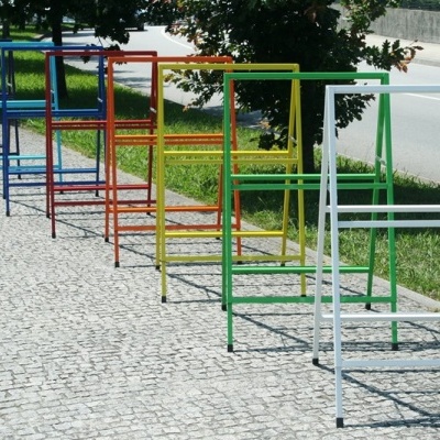 Conjunto de cabideiros metálicos coloridos alinhados numa calçada